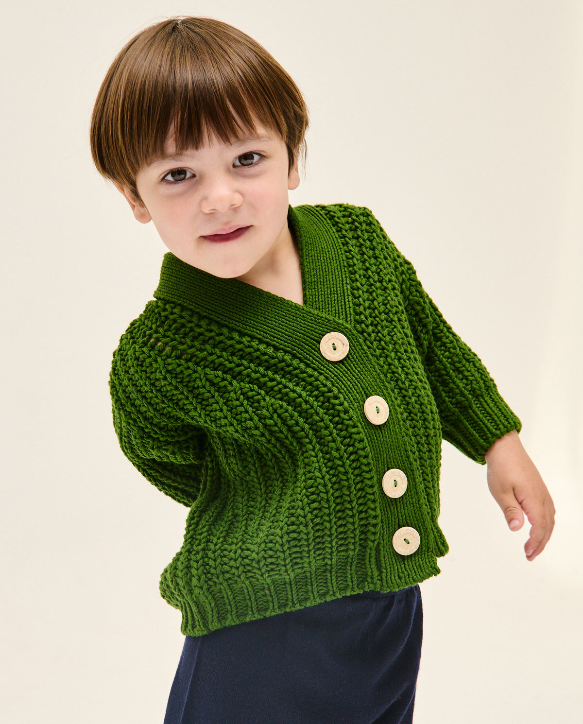 Kids' Babaà No18 pine cardigan shown in a cozy, knitted style with a front button closure and ribbed cuffs.
