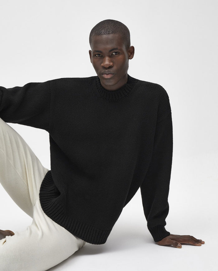 Black Babaà No16 men's jumper displayed on a hanger, showing its knit texture and classic fit.