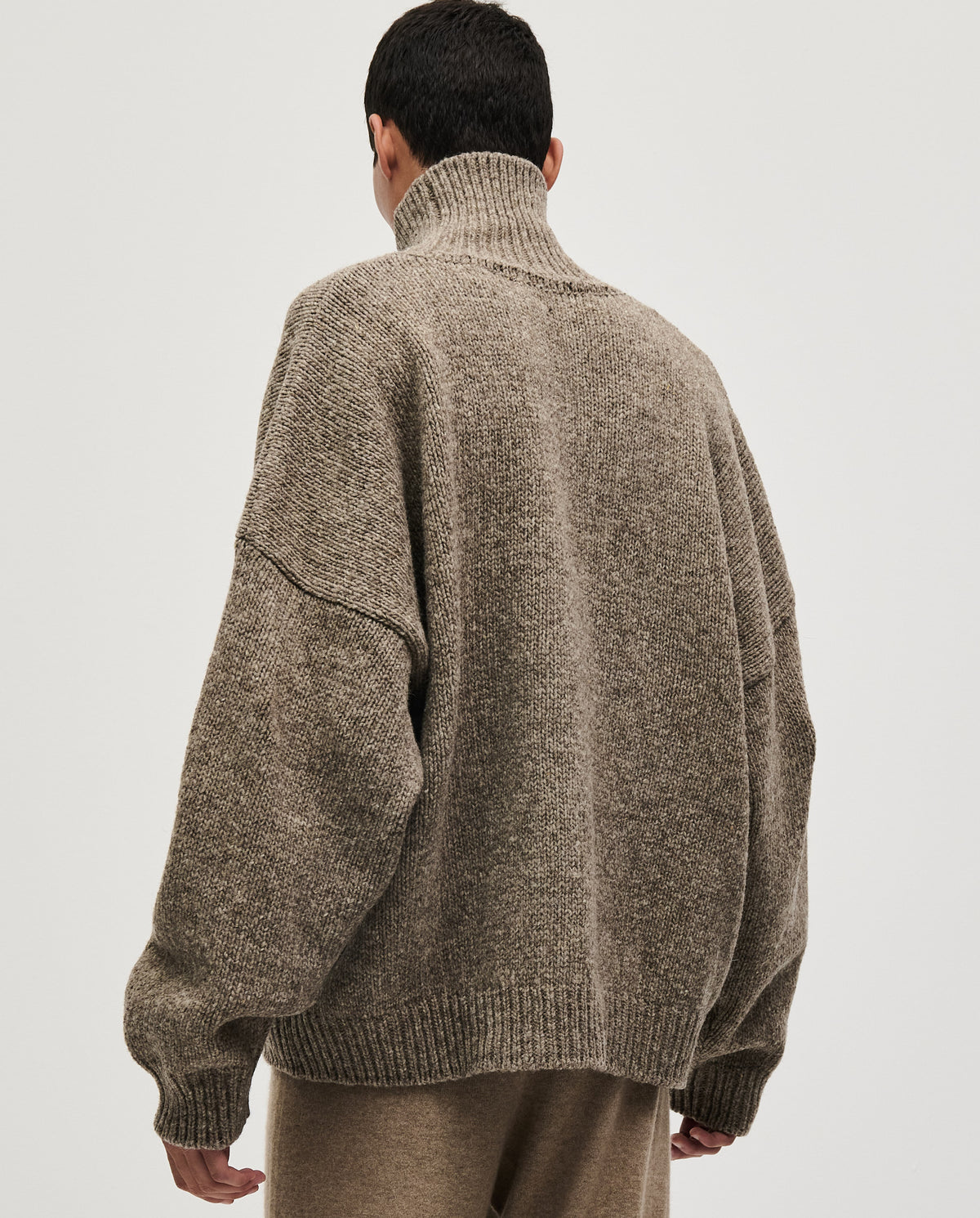 Man wearing Babaà No17 dark mist jumper, showcasing the cozy, stylish knit in a close-up outdoor setting.
