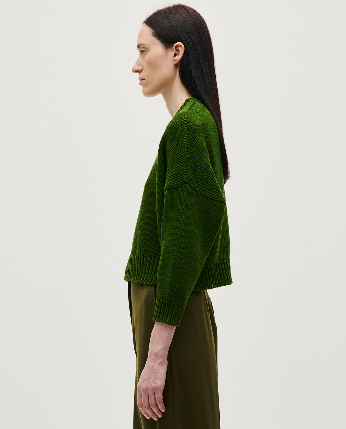 Woman wearing Babaà Jumper No14 in pine color, showcasing a cozy knit sweater with a relaxed fit and ribbed cuffs.
