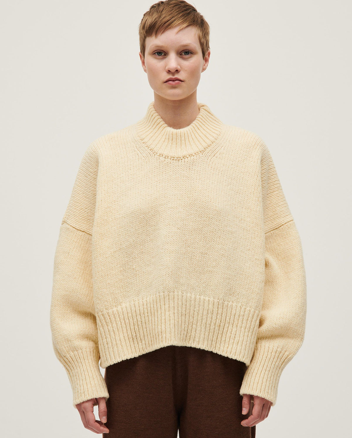 Woman wearing Babaà No15 Natural jumper, showcasing its soft knit fabric and relaxed fit in a casual outdoor setting.