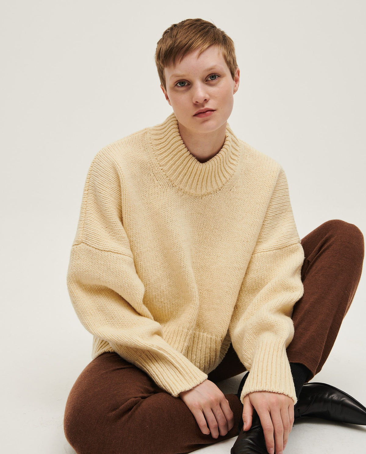 Woman wearing Babaà No15 Natural jumper, showcasing its cozy knit texture and relaxed fit in a casual indoor setting.