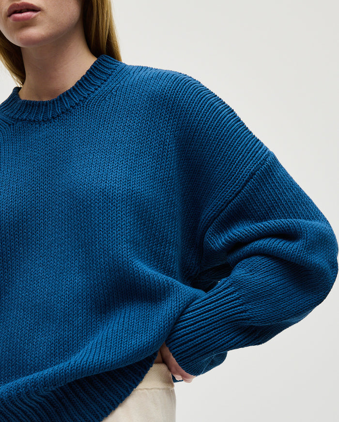 Woman wearing Babaà No16 Deep Water jumper, showcasing the stylish knit sweater with a relaxed fit and deep water blue color.