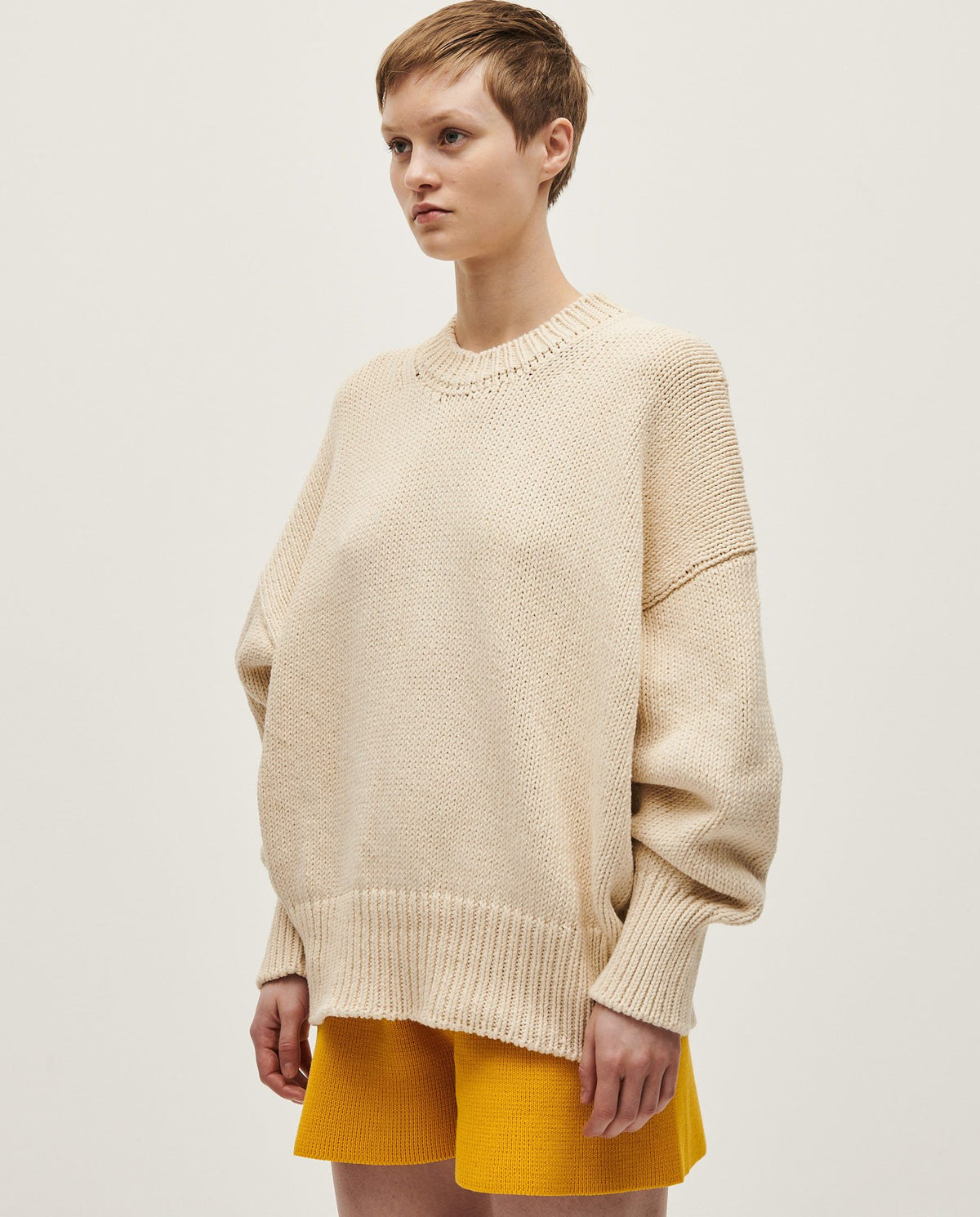 Woman wearing a natural-colored Babaà Jumper No16, featuring a cozy knit design and relaxed fit.