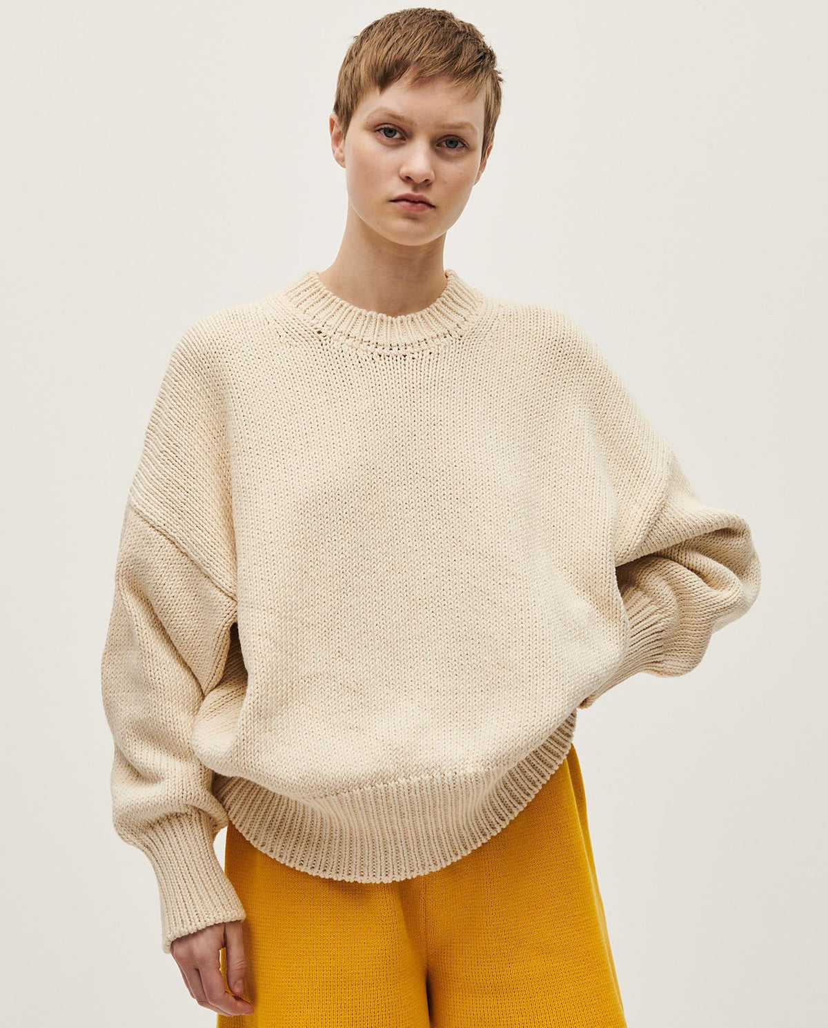 Woman wearing Babaà No16 Natural jumper, showcasing the cozy knit sweater in a natural beige color.