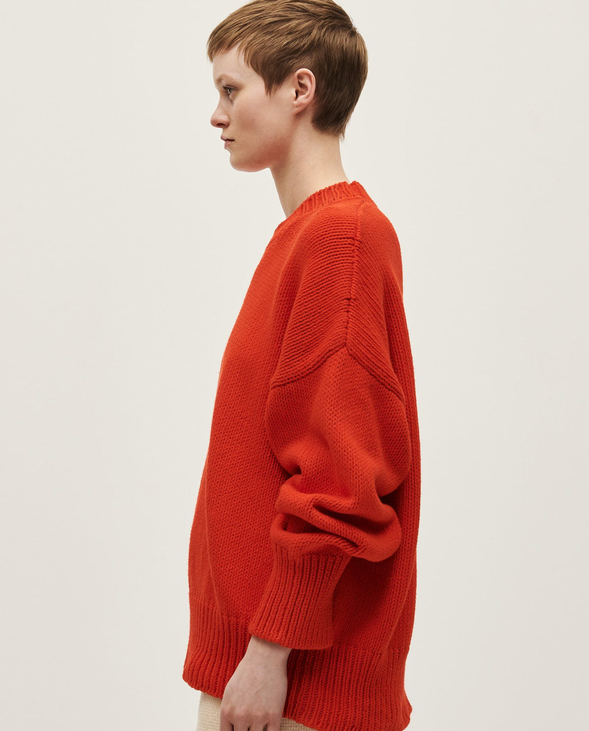 Woman wearing Babaà Jumper No16 Summer Flame, featuring a vibrant flame-colored knit sweater with a relaxed fit.