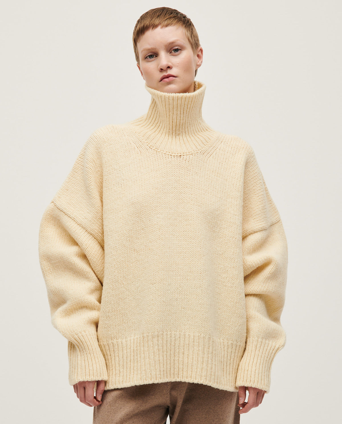Woman wearing Babaà No17 natural jumper, showcasing a cozy, neutral-colored knit sweater with a relaxed fit and soft texture.