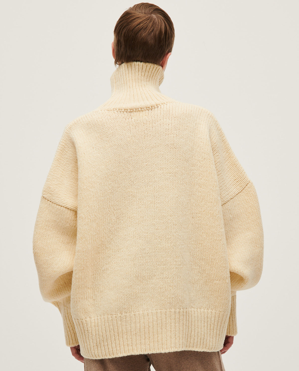 Woman wearing Babaà No17 Natural jumper, showcasing its cozy knit fabric and relaxed fit in a casual indoor setting.