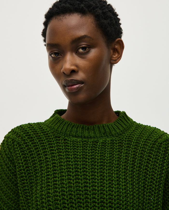 Woman wearing Babaà Jumper No18 Pine, a cozy knitted sweater in green with a relaxed fit and ribbed cuffs.