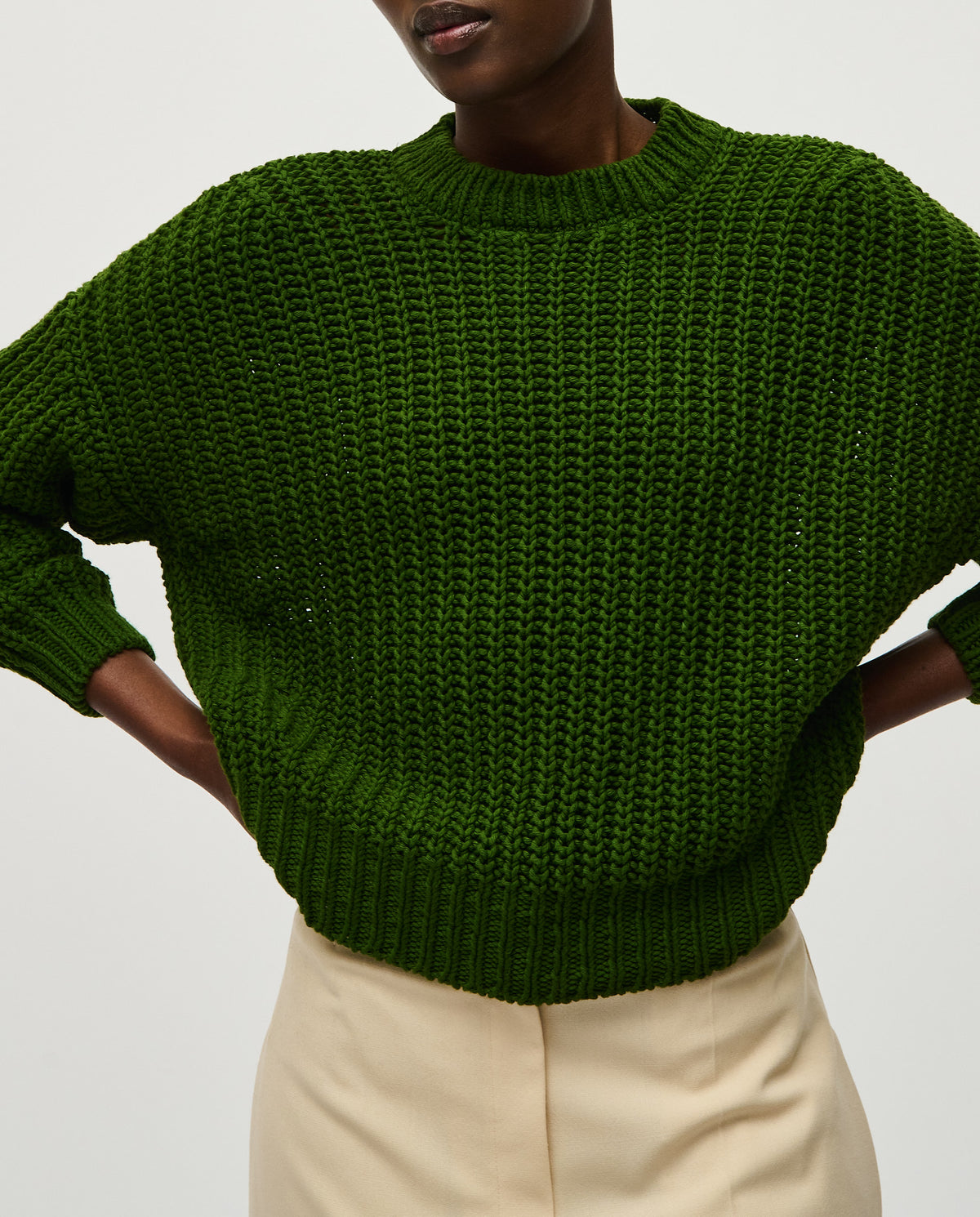 Woman wearing Babaà Jumper No18 Pine, a cozy knit sweater in a rich pine green color, shown on a white background.