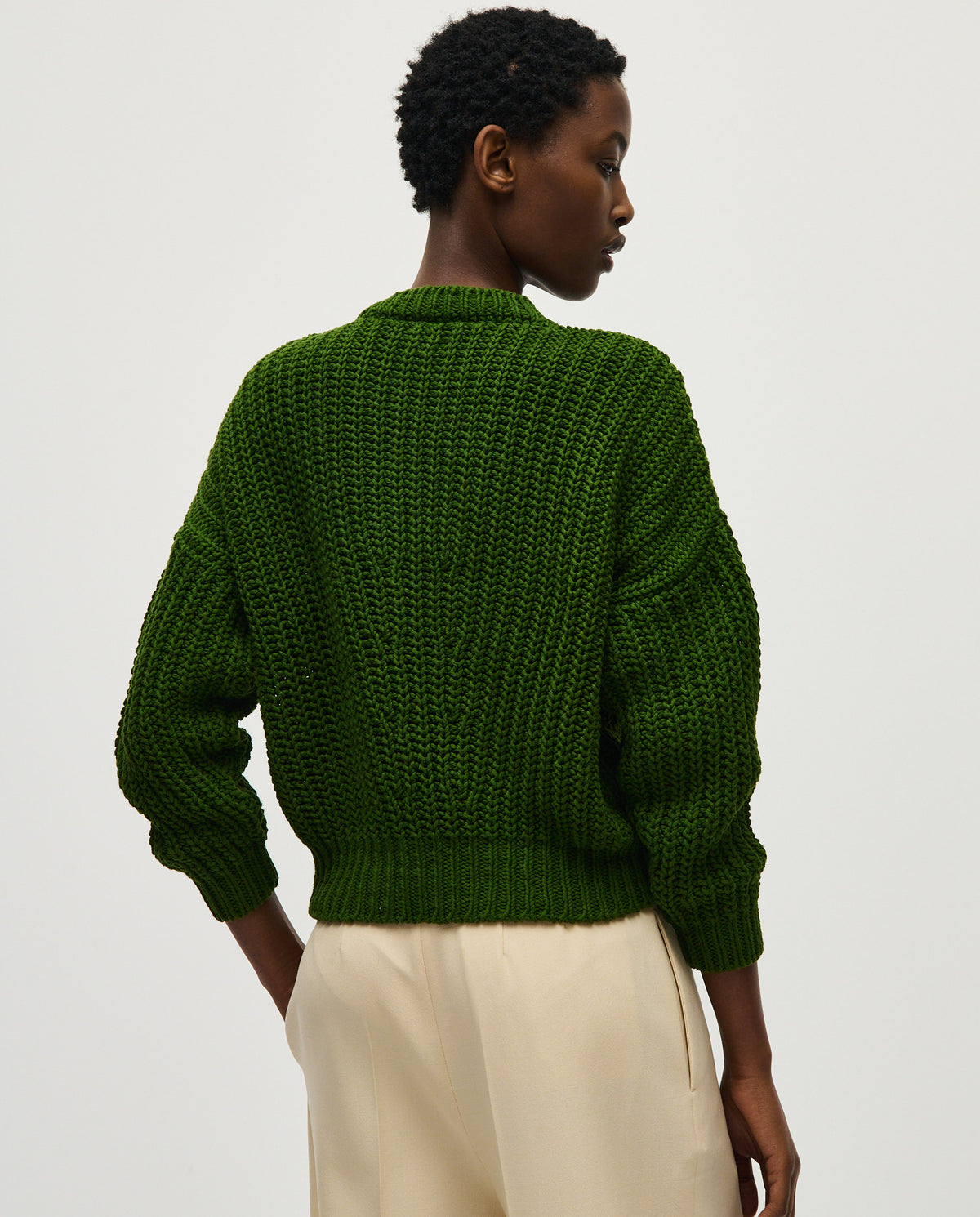 Woman wearing Babaà No18 Pine jumper, showcasing the cozy, knitted design in a natural pine color.