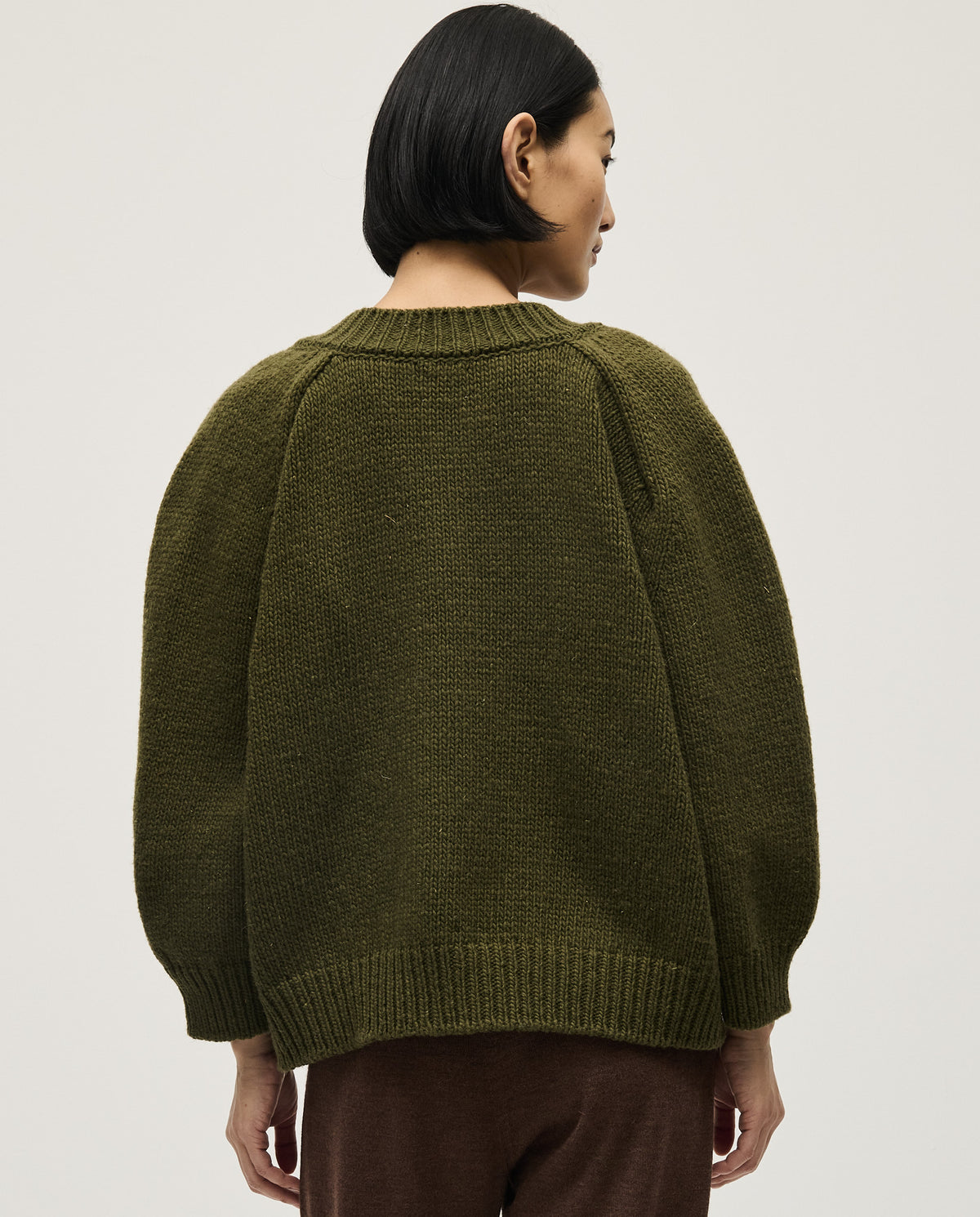 Woman wearing Babaà No29 Alga jumper featuring a cozy knit design and vibrant green color.