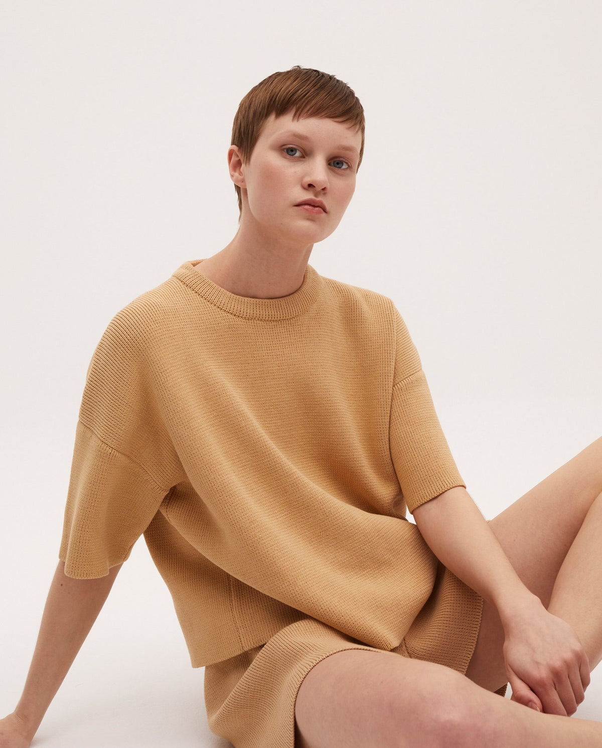 Woman wearing Babaà No35 jumper holding a rustic clay pot, showcasing stylish knitwear and a natural, cozy look.