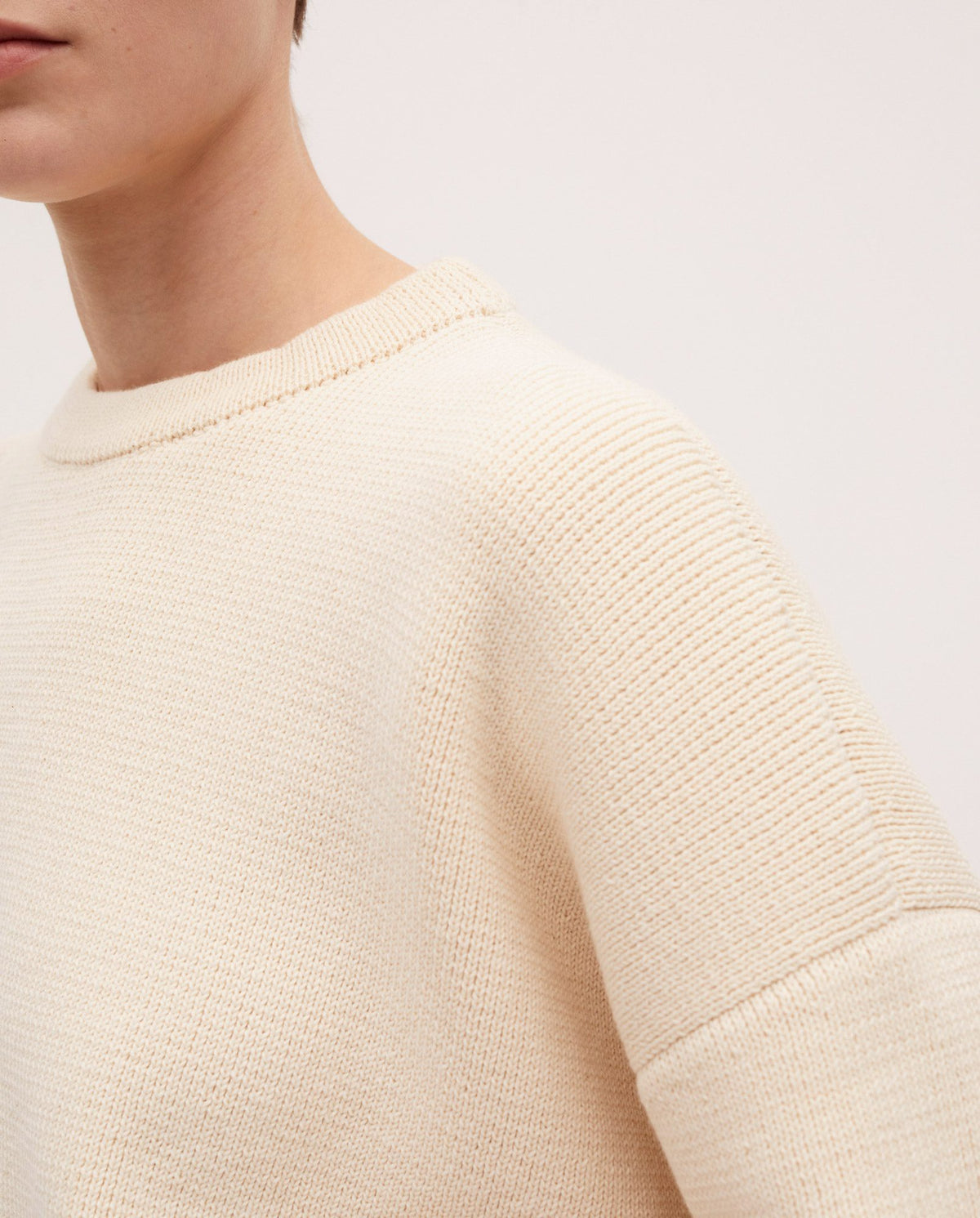 Woman wearing Babaà No35 natural jumper, showcasing the cozy, knitted design in a neutral color on a casual outdoor setting.