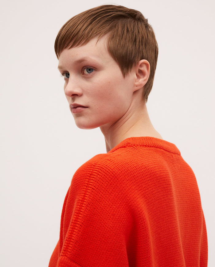 Woman wearing babaà No35 Tangelo jumper in vibrant orange, showcasing a cozy, stylish knit sweater.