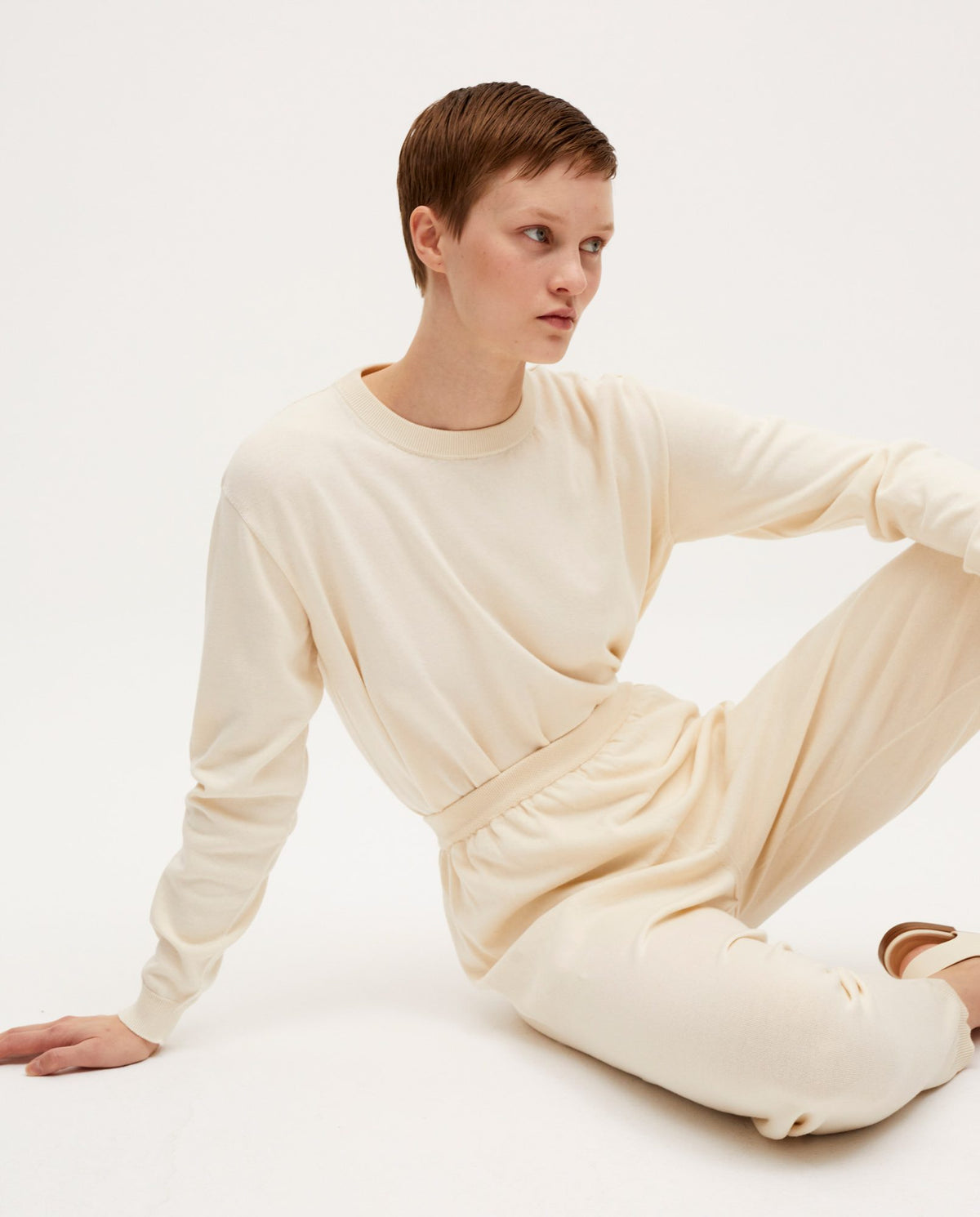 Woman wearing Babaà No37 natural jumper, showcasing its soft knit fabric and relaxed fit in a casual indoor setting.