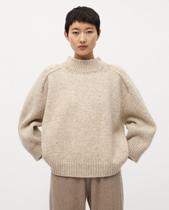 Woman wearing Babaà No51 Mist jumper, showcasing the soft knit fabric and relaxed fit in a stylish, neutral-toned design.