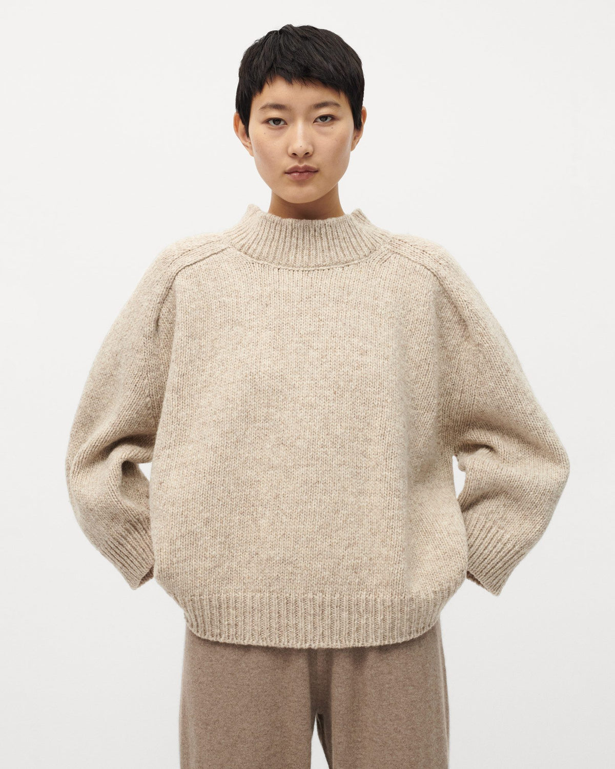 Woman wearing Babaà No51 Mist jumper, showcasing the soft knit fabric and relaxed fit in a stylish, neutral-toned design.