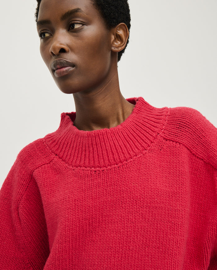 Woman wearing Babaà No51 Ruby jumper in a cozy, vibrant red knit, showcasing its stylish design and comfortable fit.