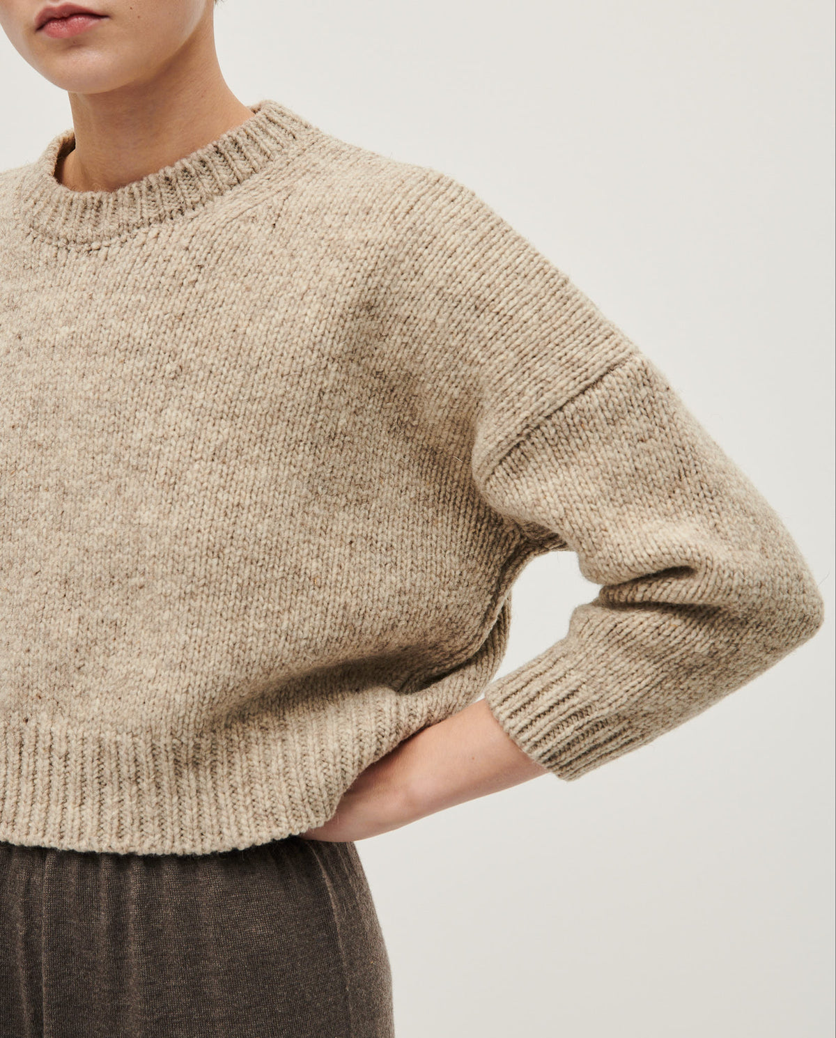 Woman wearing Babaà No61 Mist jumper, showcasing its cozy, stylish knit design and soft fabric in a casual outdoor setting.