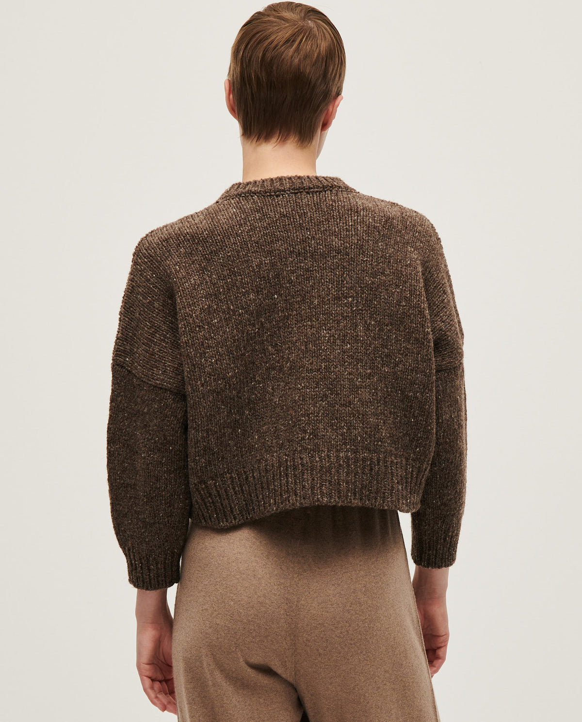 Woman wearing Babaà No61 Oak jumper, a cozy knit sweater in warm beige with a relaxed fit and ribbed cuffs.