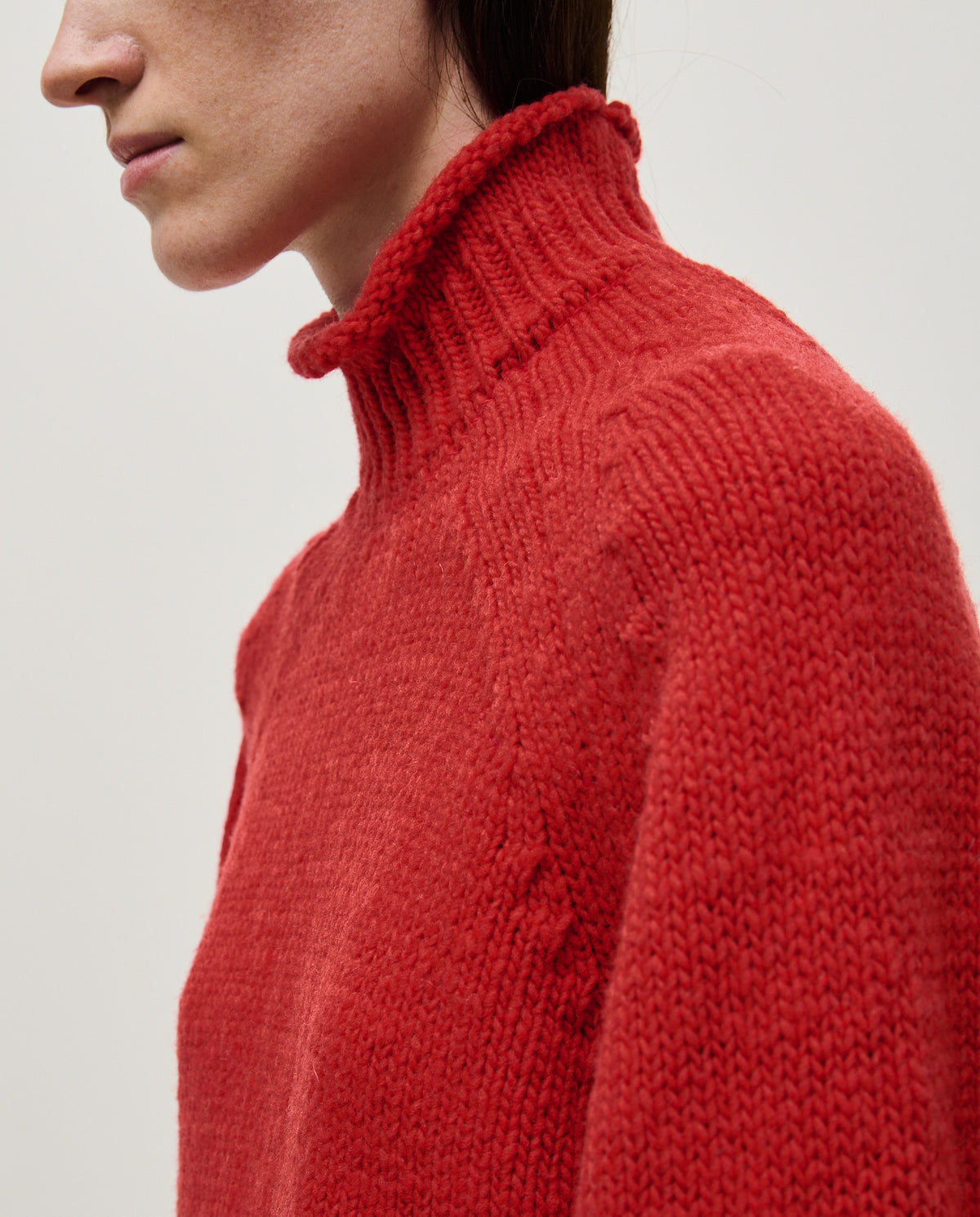 Woman wearing Babaà No70 red jumper, cozy knit sweater with long sleeves and ribbed cuffs, styled casually.