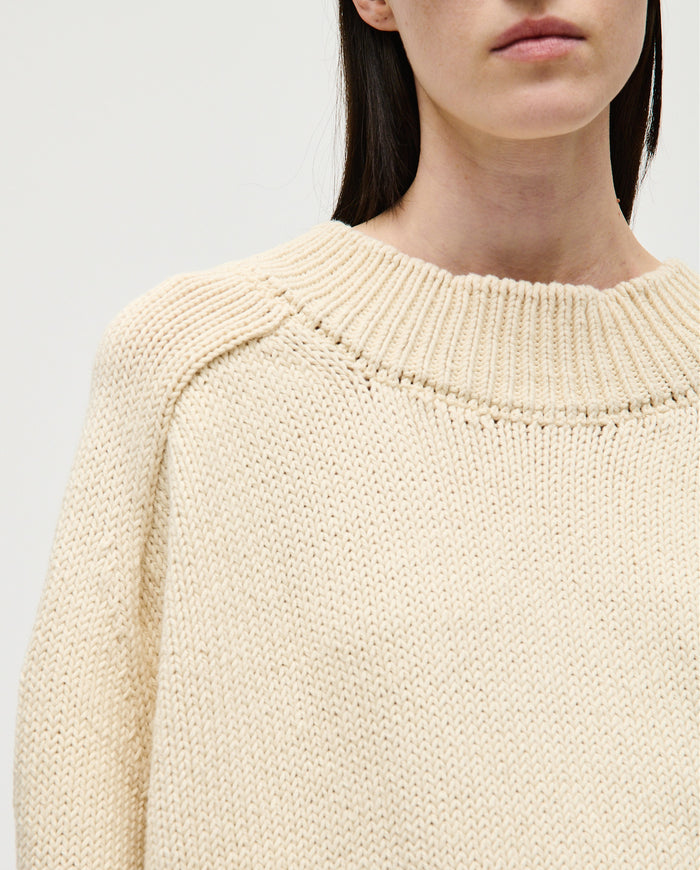 Woman wearing Babaà No72 natural jumper, showcasing the cozy, knitted beige sweater with a relaxed fit and textured fabric.