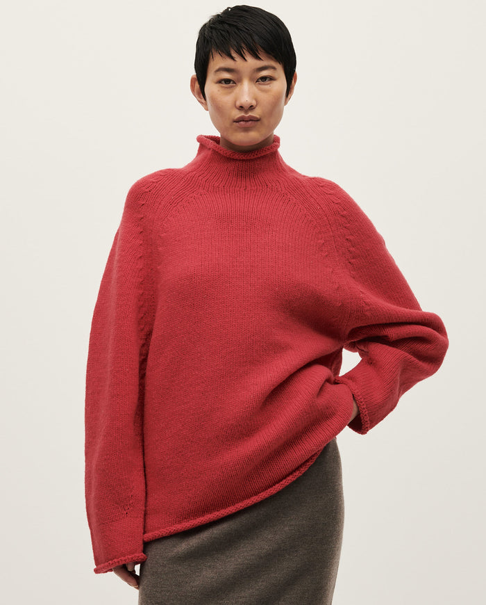 Woman wearing Babaà No81 Ruby jumper, showcasing the vibrant red knit sweater with a cozy fit and stylish design.