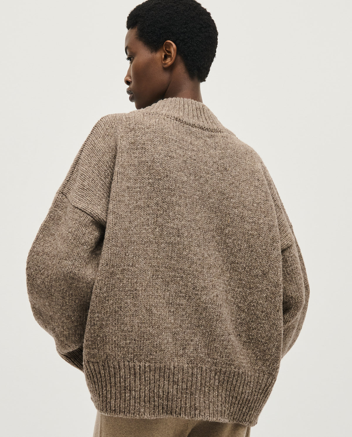 Woman wearing Babaà No87 dark mist jumper, showcasing its cozy fit and soft fabric in a casual indoor setting.