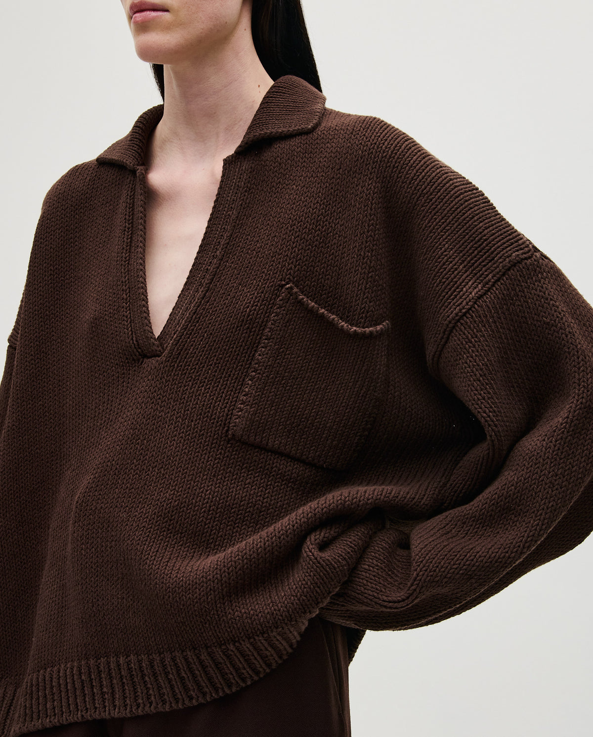 Woman wearing Babaà Polo No1 Husk, a stylish polo shirt in a natural husk color, shown on a model in a casual setting.