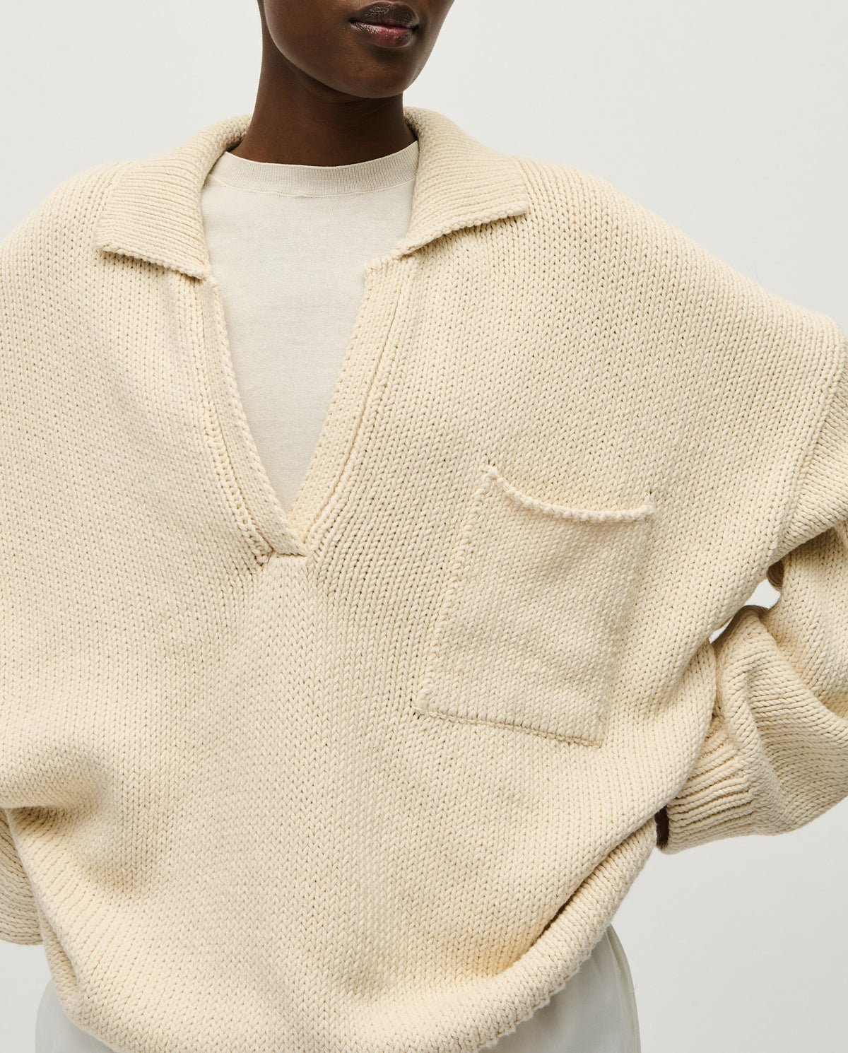 Woman wearing a natural-colored Babaà Polo No1 shirt, showcasing its classic fit and soft cotton fabric.
