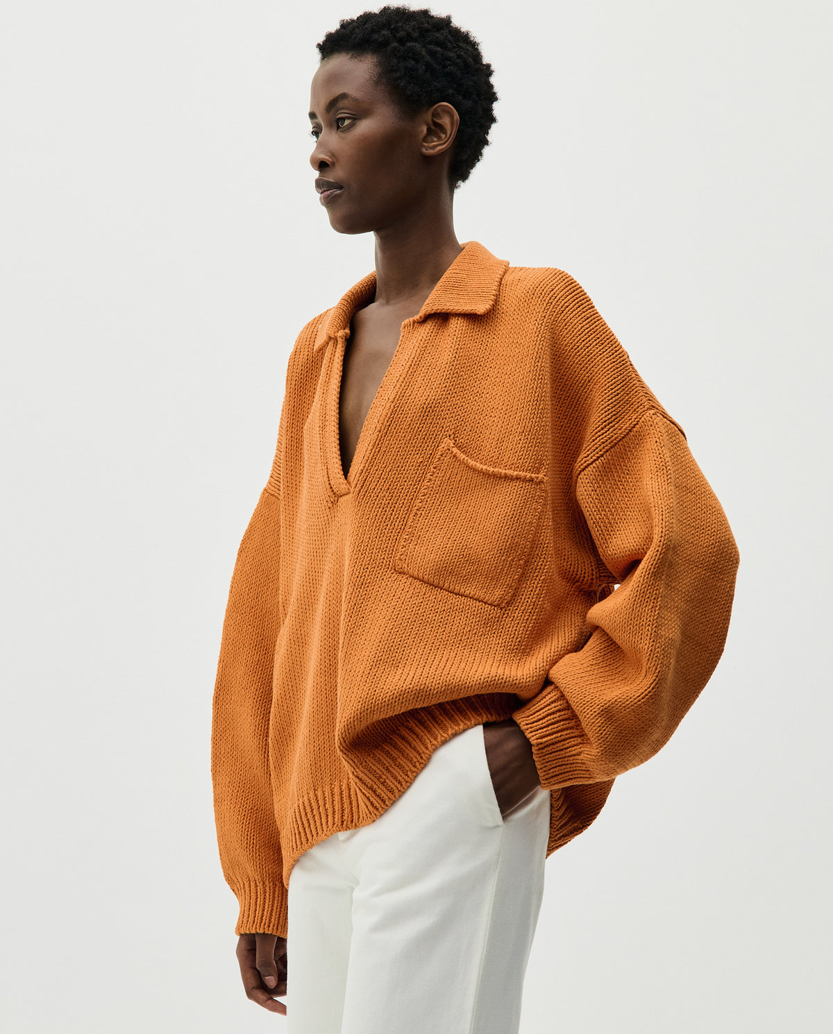 Woman wearing Babaà Polo No1 in Persimmon, showcasing the vibrant orange collared shirt with a relaxed fit.