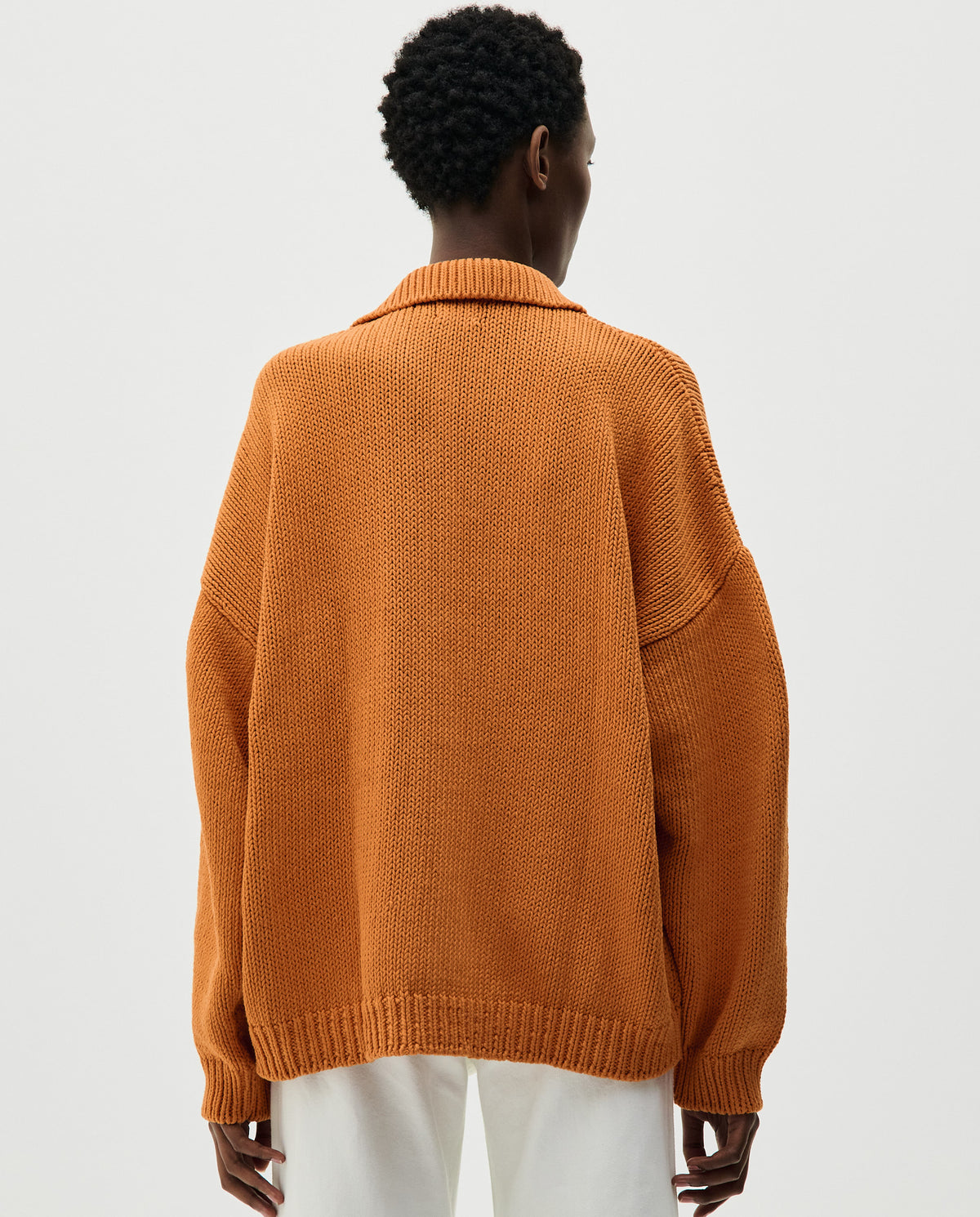 Woman wearing a Babaà Polo No.1 in Persimmon, featuring a classic fit and vibrant orange color, shown on a model.