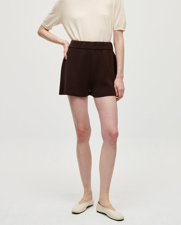 Woman wearing Babaà No35 Husk shorts, lightweight beige linen shorts with a relaxed fit, styled casually.
