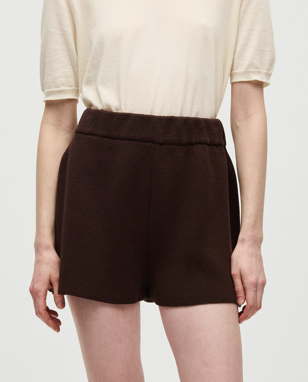 Woman wearing Babaà No35 Husk shorts, lightweight beige cotton shorts with a relaxed fit, front pockets, and casual style.
