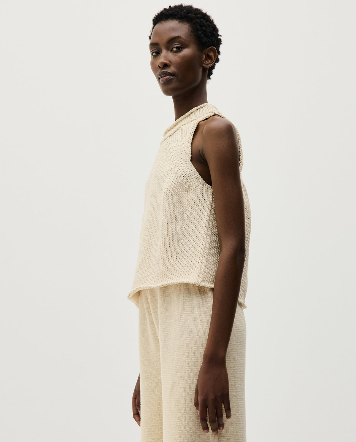 Woman wearing Babaà Top No46 Natural, stylish sleeveless top in soft natural fabric, close-up of the fitted neckline and fabric texture.
