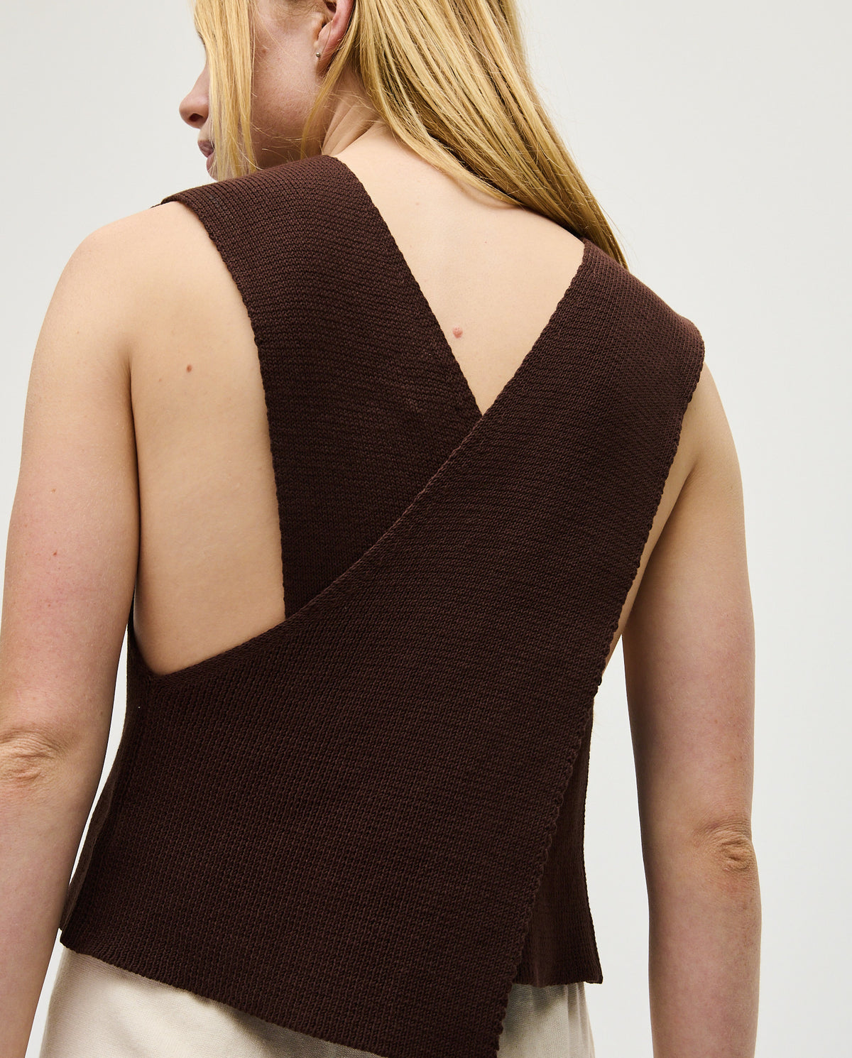 Woman wearing Babaà Top No85 Husk, stylish sleeveless blouse with a textured fabric and elegant design.