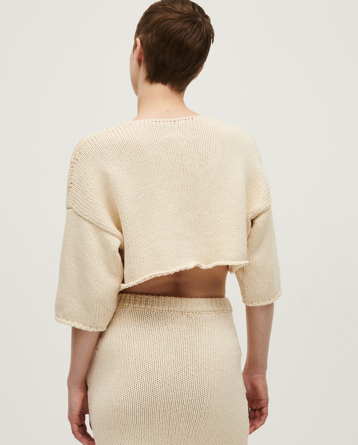 Woman wearing Babaà Top No9 Natural, a stylish sleeveless top in a natural fabric, displayed on a model.