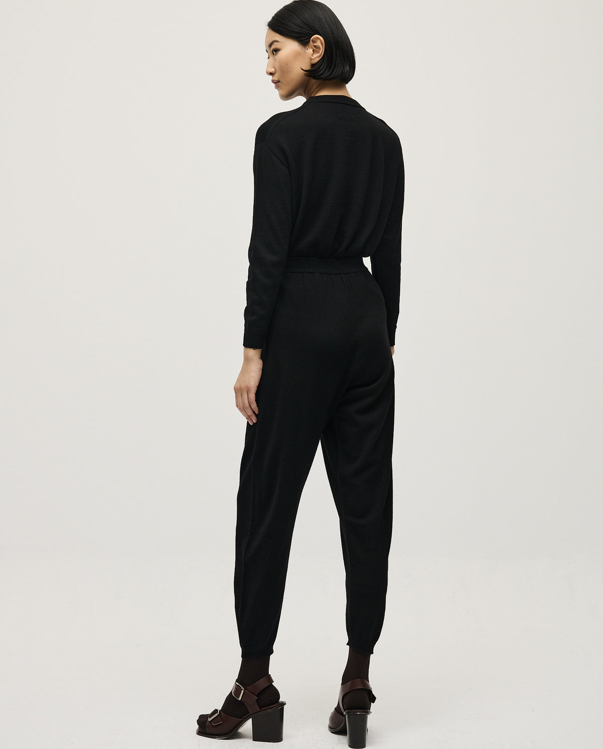 Black Babaà No25 women's trousers with a tailored fit, shown hanging on a rack with a smooth fabric texture.