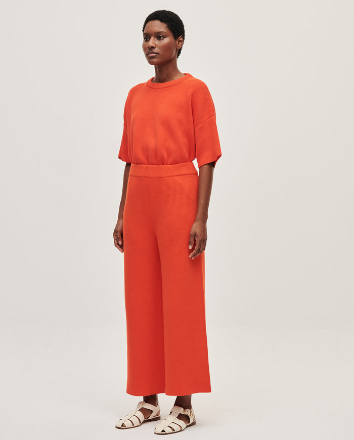 Babaà No35 Tangelo women's trousers with a relaxed fit and vibrant orange color, shown on a model in a casual setting.