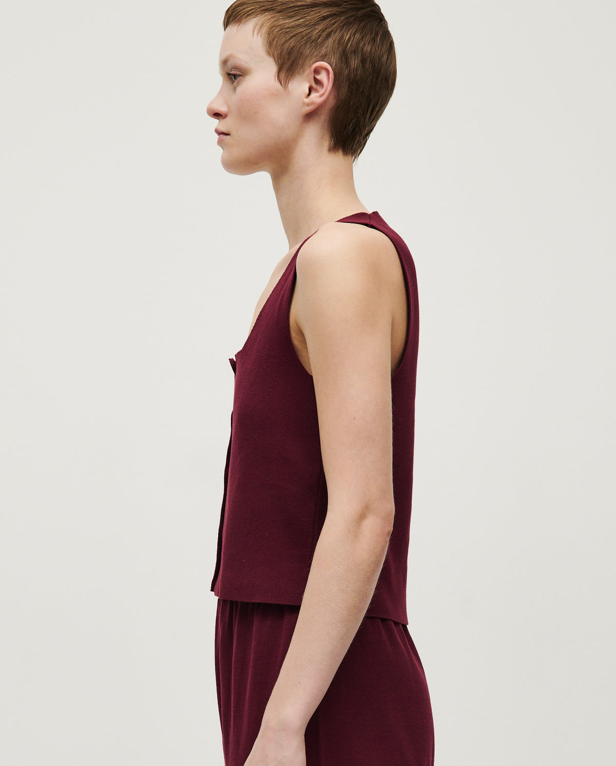 Woman wearing Babaà No39 Cherry vest, showcasing a stylish sleeveless vest with a vibrant cherry color and fitted design.