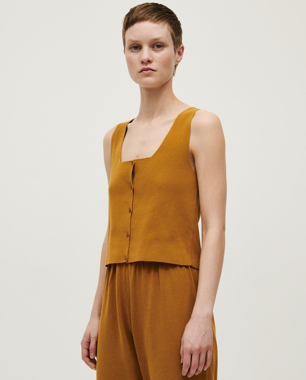 Babaà No39 senape women's vest displayed hanging, featuring a vibrant yellow color and sleeveless design.