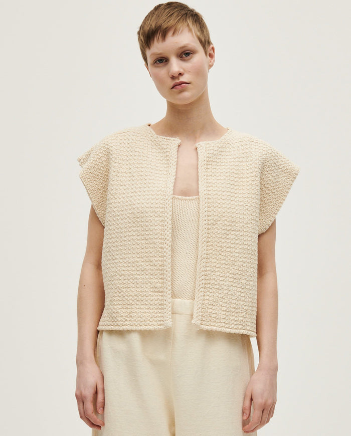 Woman wearing Babaà No8 Natural vest, showcasing soft, neutral-colored sleeveless top made from comfortable fabric.